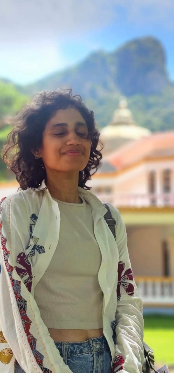 Likhitha Sree in quiet meditation at a temple backdrop — consultation portrait