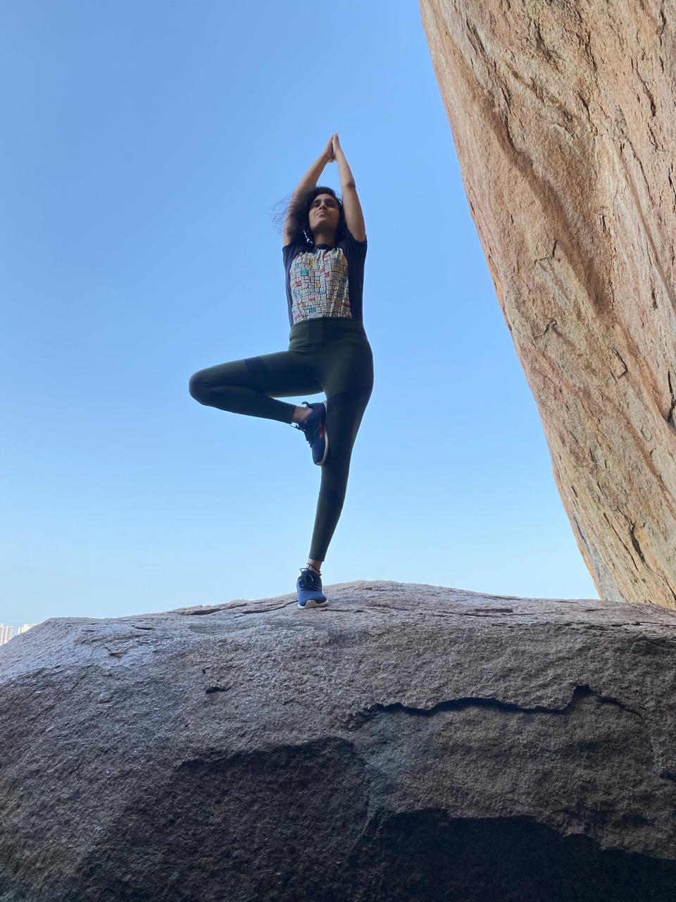 Likhitha in tree pose shot from low angle against rock — early practice years